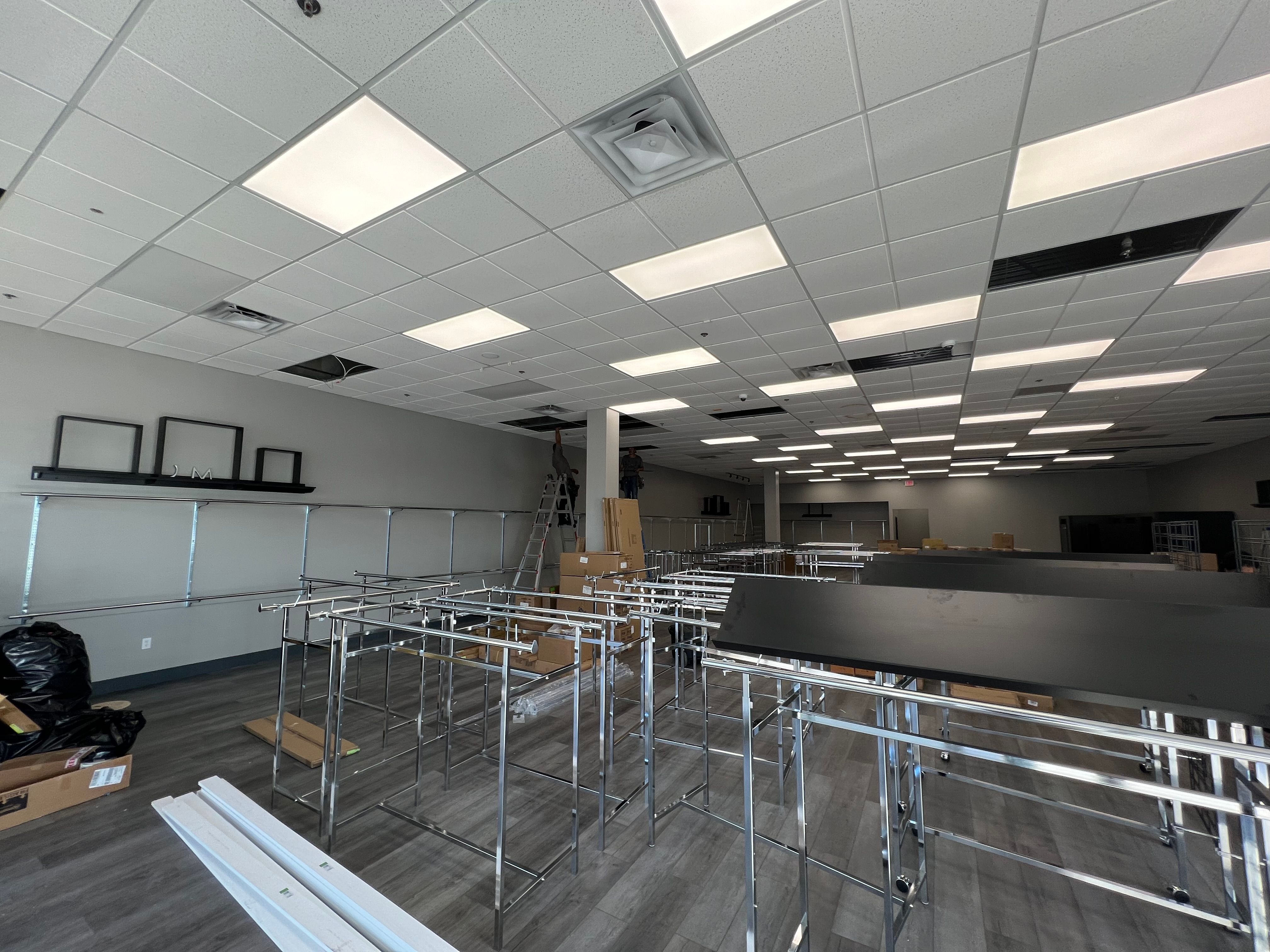 Wide shot of an empty room with numerous partially assembled metal shelving units.