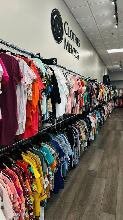 Colorful garments are neatly displayed on racks inside a bright, modern clothing store, offering a wide selection of apparel.