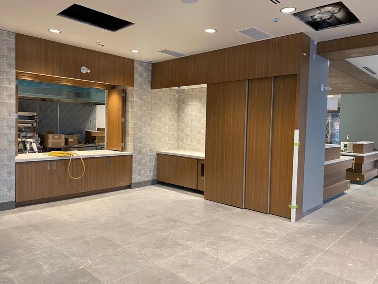 A newly constructed commercial kitchen area displays modern wood paneling and a serving window, awaiting final finishes.