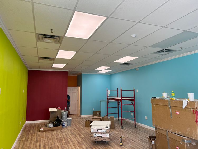 A vibrant salon interior boasts lime green, magenta, and light blue walls, equipped with modern styling chairs.