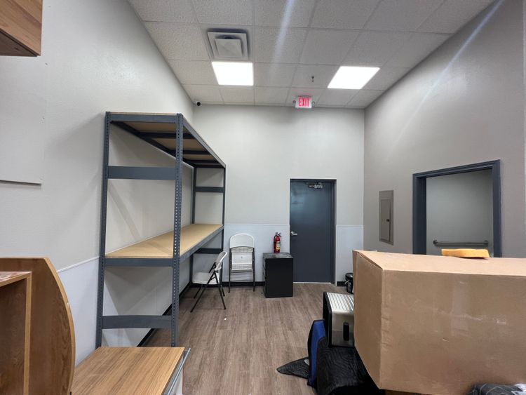 This image shows a vacant commercial interior featuring metal shelves and an unfinished reception counter.