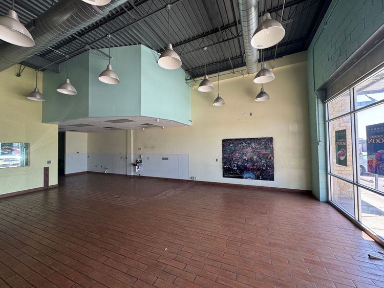 The large, open commercial space features hardwood flooring, an exposed ceiling, and a prominent light green bulkhead.