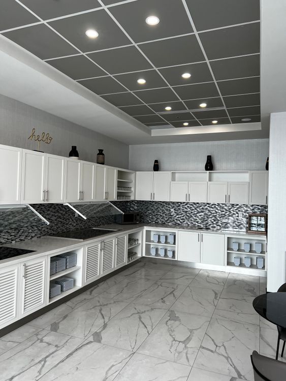 This neat and modern kitchen area boasts ample white storage cabinets and a stylish dark tiled backsplash.