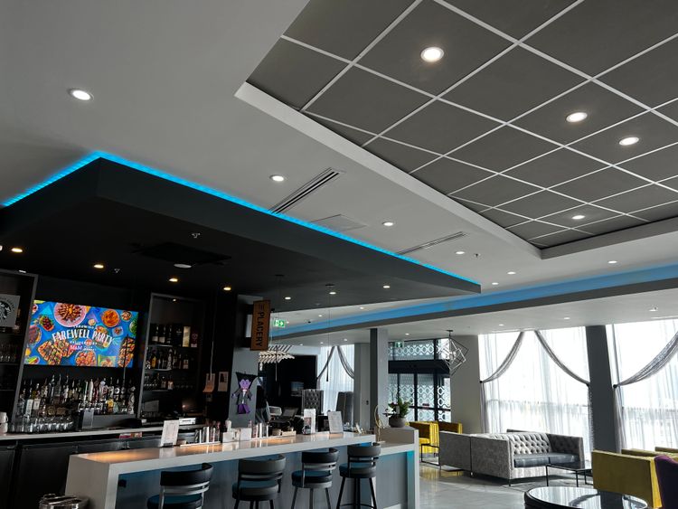 This contemporary bar features sleek design, vibrant blue lighting, and a large screen, perfect for evening relaxation.