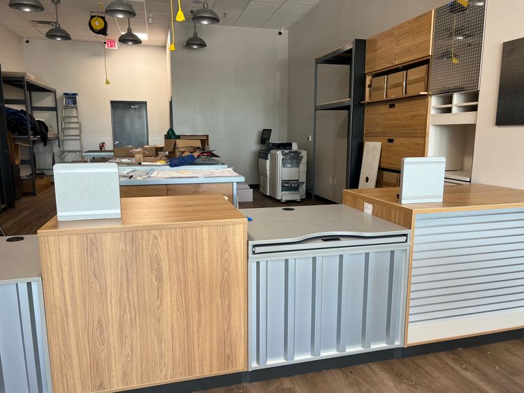 The reception area features a stylish counter with integrated speakers and a work area behind it.