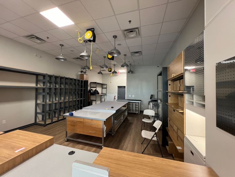 This expansive workroom is equipped with long tables and extensive shelving, prepared for various tasks.