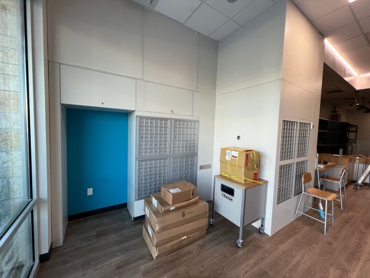 A section of the interior dedicated to mailboxes and a blue door, with several cardboard boxes awaiting processing.