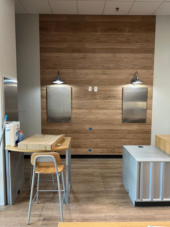 A decorative wooden wall features two square mirrors and chic light fixtures, with a modern chair in the foreground.